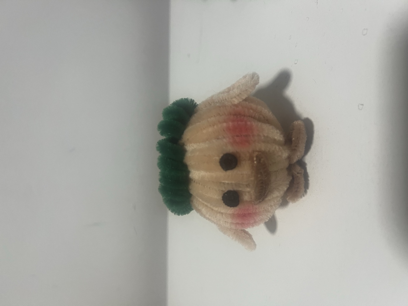 Handmade peach chick character with a green cap